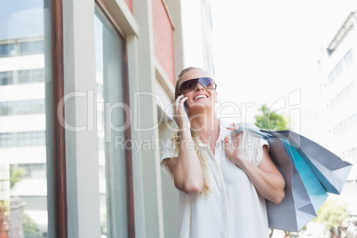 Pretty blonde making a call and holding shopping bags