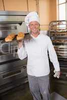 Baker holding tray of fresh bread