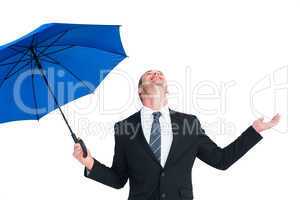 Happy businessman holding blue umbrella and looking up