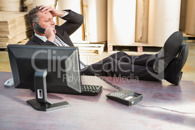 Warehouse manager using telephone at desk