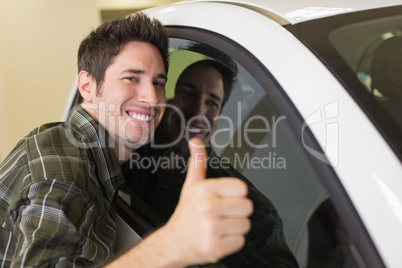 Smiling man hugging a white car while giving thumbs up