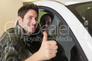 Smiling man hugging a white car while giving thumbs up