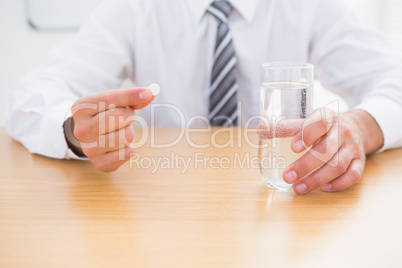 Casual businessman holding glass of water and tablet