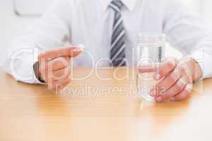 Casual businessman holding glass of water and tablet