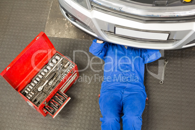 Mechanic lying and working under car