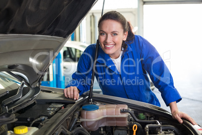 Mechanic smiling at the camera fixing engine