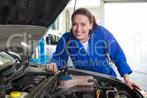 Mechanic smiling at the camera fixing engine