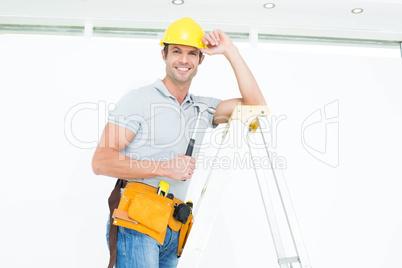 Technician holding hammer while wearing hard hat on step ladder