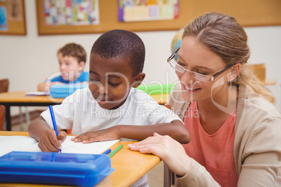 Pretty teacher helping pupil in classroom