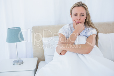 Thoughtful blonde under duvet in bed