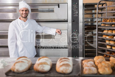 Happy baker leaning on professional oven