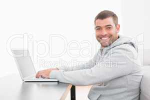 A smiling man using laptop at a table