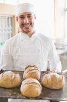 Happy baker showing tray of fresh bread