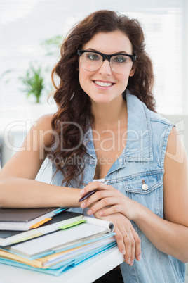 Smiling businesswoman leaning on notebooks