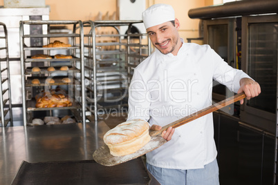 Happy baker taking out fresh loaf