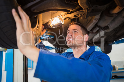 Mechanic using torch to look under car