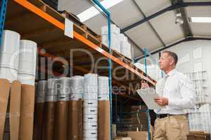 Warehouse manager checking his list on clipboard