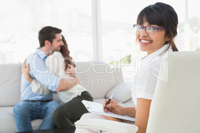 Smiling therapist with patients hugging behind her