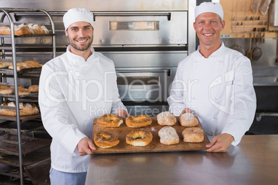 Team of bakers smiling at camera with trays of bread