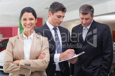 Businessman writing on clipboard talking to colleague