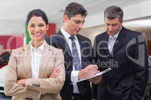 Businessman writing on clipboard talking to colleague
