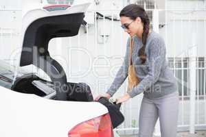 Woman pulling out a baggage of her car trunk