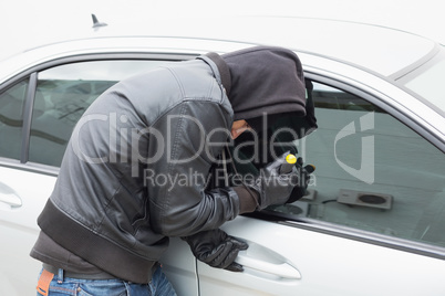 Thief breaking into car with screwdriver