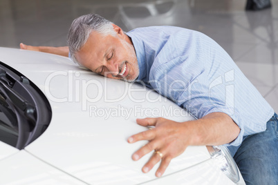 Smiling man hugging a white car