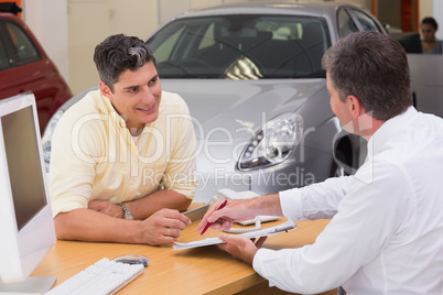 Salesman showing client where to sign the deal