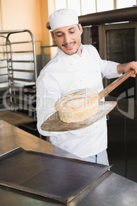 Happy baker taking out fresh loaf