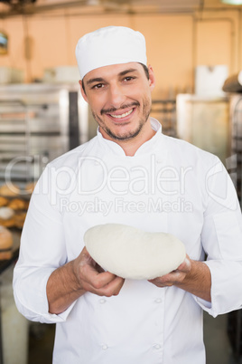 Smiling baker holding raw dough