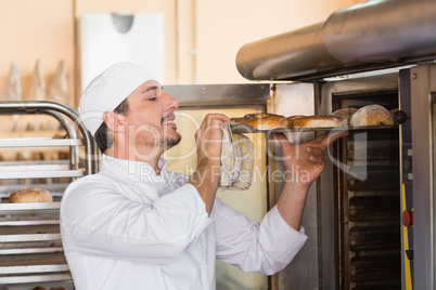 Happy baker taking out fresh bagels