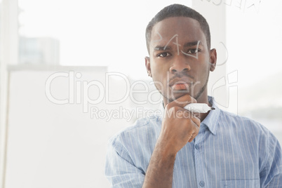 Serious businessman with hand on chin holding marker