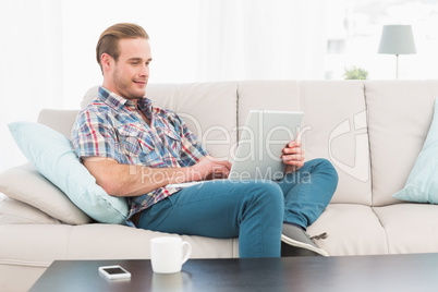 Relaxed man sitting on sofa using laptop