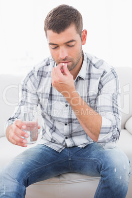 Hungover man with his medicine laid out on coffee table