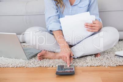 Blonde sitting on carpet using calculator