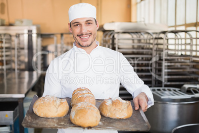 Happy baker showing tray of fresh bread