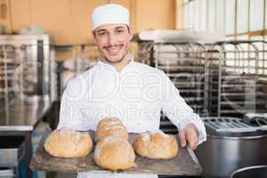 Happy baker showing tray of fresh bread