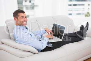 Relaxing businessman on a sofa with a laptop