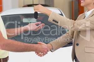 Businesswoman giving key while shaking a customer hand