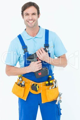 Confident carpenter holding drill machine