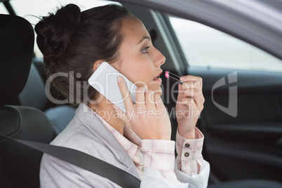 Woman having a phone call while putting on lipstick