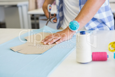 Fashion student cutting fabric with pair of scissors