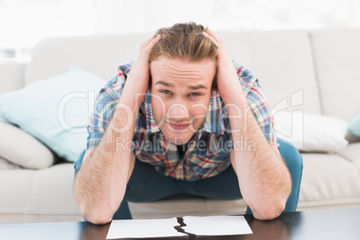 Sad man with hands on his head looking at camera