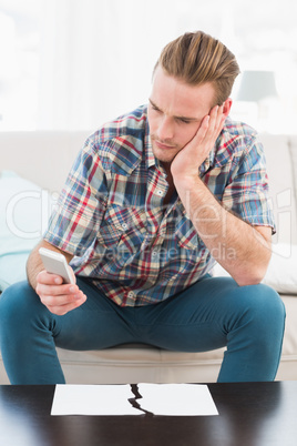 Concentrated man using mobile phone near ripped paper
