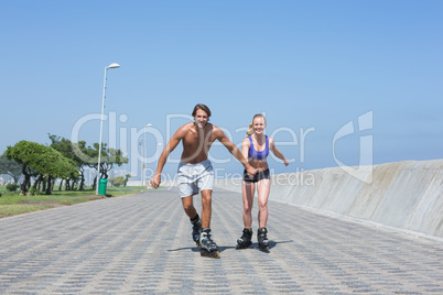 Fit couple rollerblading together on the promenade