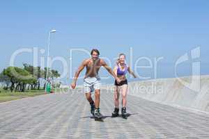 Fit couple rollerblading together on the promenade