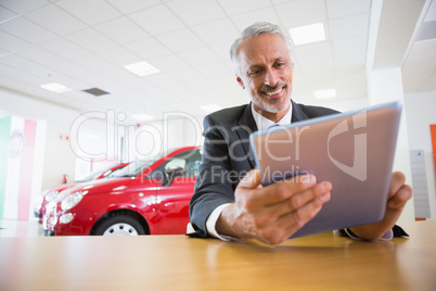 Smiling businessman using tablet at his desk