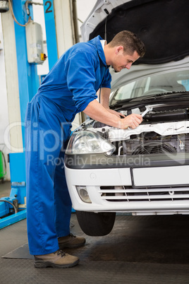 Mechanic examining under hood of car