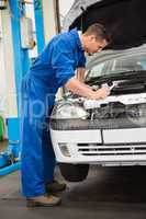 Mechanic examining under hood of car